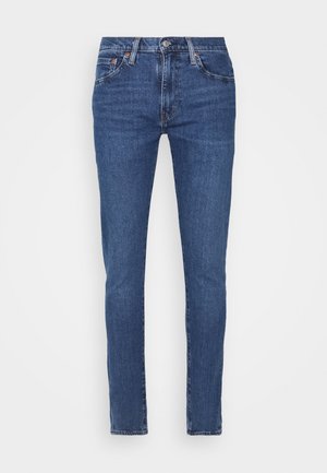 Sötétkék farmernadrág, slim fit szabással, öt zsebbel, enyhe elhalványulással és kontrasztos varrással. Gombos és cipzáras záródással rendelkezik.