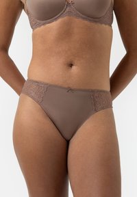 Bruine beha met kant en bijpassend ondergoed, gedragen door een persoon met een gemiddeld donkere huidtint, weergegeven van de taille tot boven de dijen.