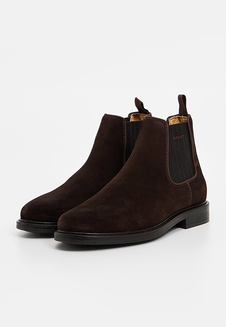 Brązowe zamszowe botki typu Chelsea, z elastycznymi bokami, akcentami w postaci przeszyć i niskim, ułożonym obcasem. Gładkie wnętrze zapewniające dodatkowy komfort.