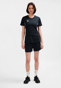 Tenue de sport noire comprenant un t-shirt à manches courtes et un short, fabriquée en tissu respirant avec une texture lisse et un marquage minimal.