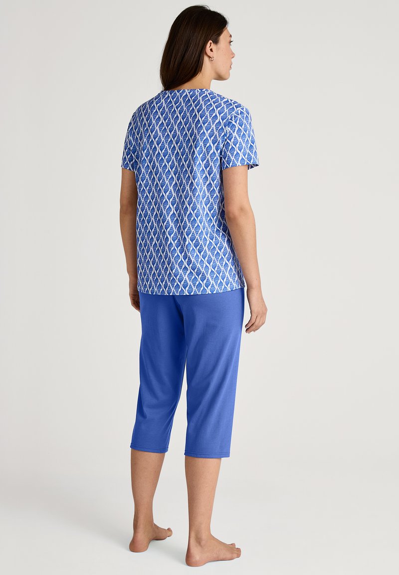 Blauwe katoenen pyjama top met een patroon en korte mouwen, gecombineerd met effen blauwe capri-broekjes. Zacht stof met een ontspannen pasvorm.