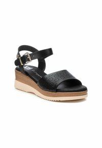 Sandalo wedge in pelle nera con design perforato, cinturino alla caviglia regolabile e suola in gomma bicolore con finitura testurizzata.
