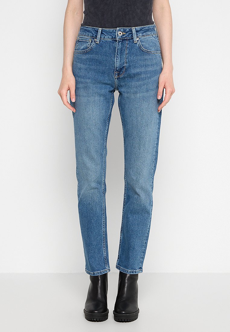 Stretch-Denim-Jeans in Hellblau, mit einem klassischen Fünf-Taschen-Design und geradem Bein. Getragen mit schwarzen Stiefeletten.