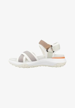 Des sandales blanches avec une semelle épaisse blanche, dotées de sangles élastiques gris et beige et d'un accent orange contrastant à l'arrière du talon.