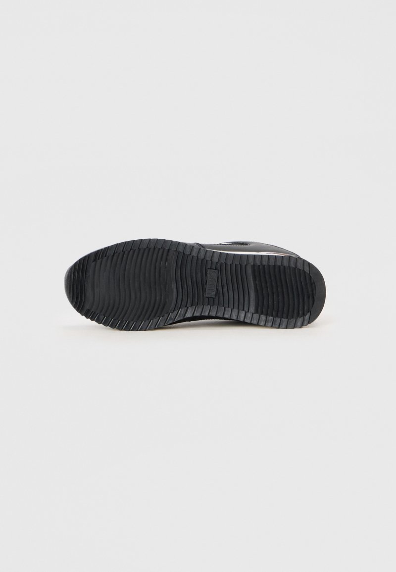 Suela de zapato negro con superficie de goma texturizada que presenta ranuras horizontales y verticales para tracción, puntera redondeada y un talón plano.