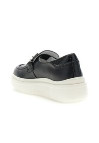 Scarpa in pelle nera con finitura testurizzata, punta ovale, suola in gomma bianca e una fibbia decorativa sul lato. Presenta un tacco liscio.