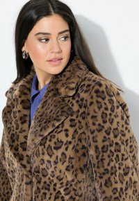 Faux furjakke med leopardmønster, der har en bred krave og blød tekstur. Brun bund med mørke pletter, struktureret silhuet.