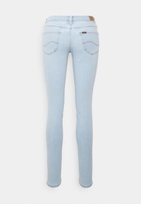 Jeans skinny de color azul claro vistos desde atrás, con dos bolsillos traseros con detalle de costura y un pequeño parche de cuero con la marca en la cinturilla.