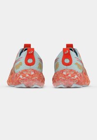 Μπλε αθλητικά παπούτσια με υφασμάτινο επάνω μέρος με υφή, κόκκινες λεπτομέρειες και διαφανές, κυματιστό πορτοκαλί πέλμα. Διαθέτουν λογότυπο και διακοσμητικά σχέδια.