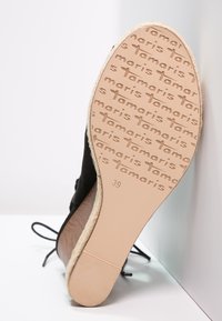 Scarpa in suede nera con suola marrone chiaro. Caratterizzata da un marchio stampato e dalla taglia "39" sulla suola, con un bordo texturizzato per la presa.