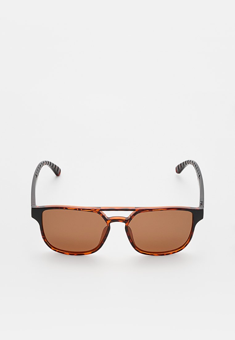 Okulary przeciwsłoneczne z oprawkami w kolorze żółwia, brązowymi soczewkami i czarnymi, teksturowanymi ramionami. Posiadają podwójny mostek i prostokątny kształt.
