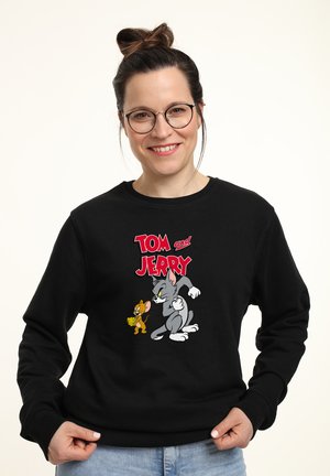 Sweatshirt noir avec des personnages de dessin animé Tom et Jerry dans des couleurs vives. Design à col rond avec une texture douce.
