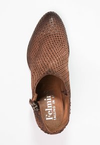 Bota de cuero marrón perforada hasta el tobillo con punta afilada, costuras decorativas, cremallera lateral y un forro interior suave.