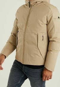 Beżowa kurtka puchowa z przednim zamkiem błyskawicznym, regulowanym kapturem i zamykanymi na zamek kieszeniami. Gładka faktura, ocieplony fason i sylwetka o dopasowanym kroju.