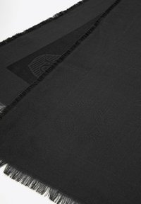 Bufanda negra con bordes con flecos, que presenta un sutil patrón en relieve. El material parece suave y texturizado, con un color oscuro uniforme.