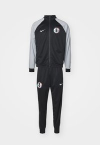 Μαύρο φόρμα Nike με γκρι λεπτομέρειες, περιλαμβάνει ζακέτα με φερμουάρ και παντελόνι με ελαστική μέση, περιλαμβάνει λογότυπο στη ζακέτα και στα παντελόνια.