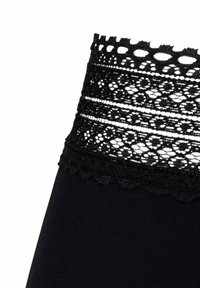 Leggings noires avec une ceinture en dentelle noire décorative, aux bords festonnés et aux motifs de rayures horizontales. Texture douce et extensible.