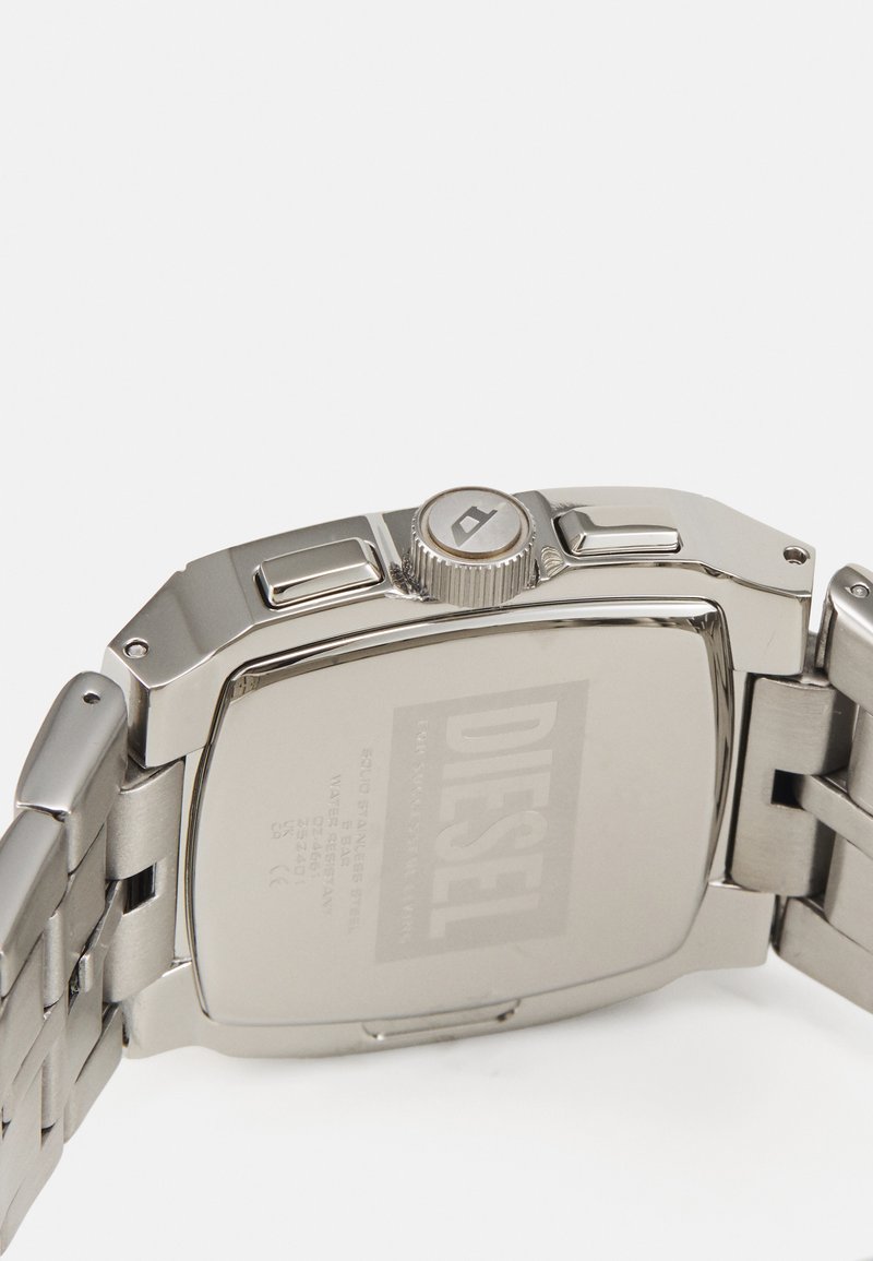 Silberne Edelstahl-Uhr mit rechteckigem Gehäuse, strukturiertem Kranz und gebürstetem Metallarmband. Graviertes Logo und Details auf der Rückseite.