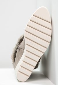 Sko med en beige ruskindsoverdel og faux fur kant, med en tekstureret hvid gummisål med riller og branding, størrelse 37 synlig.