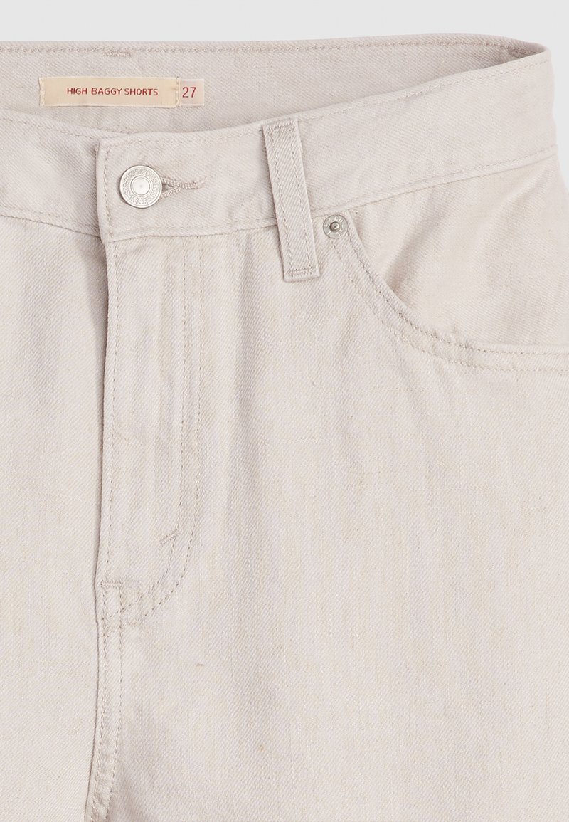Hohe, weite Shorts aus hellem beigen Denim. Mit einem vorderen Knopf mit metallischem Akzent und klassischem Fünf-Taschen-Design.