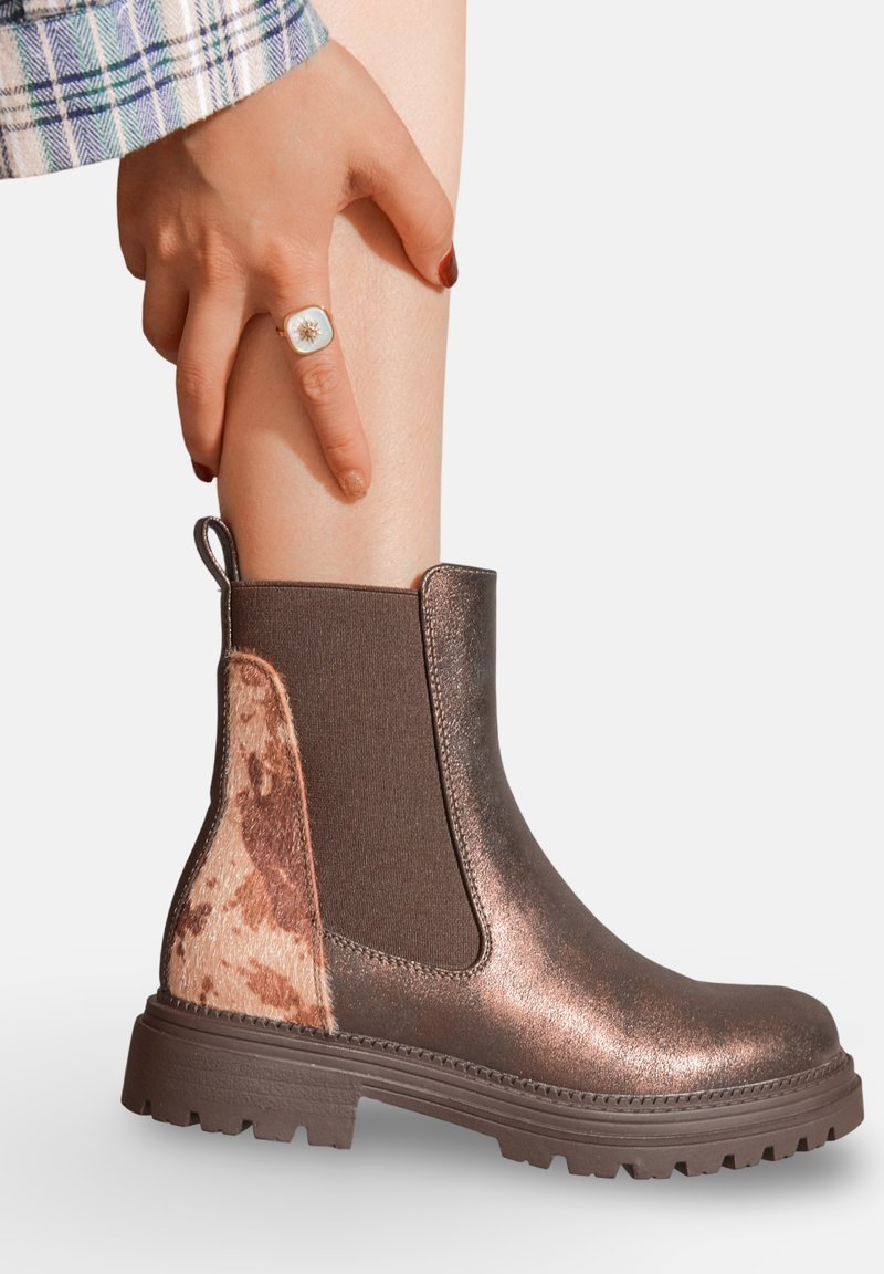Bottine en bronze métallique avec côtés élastiques, panneau en tissu texturé, semelle robuste et accents beige clair contrastants. Design durable.