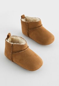 Bottillons pour bébé en suède marron avec un intérieur en fausse fourrure douce, des orteils ronds et une couture décorative le long des coutures. Deux petites languettes de traction sur le dessus.