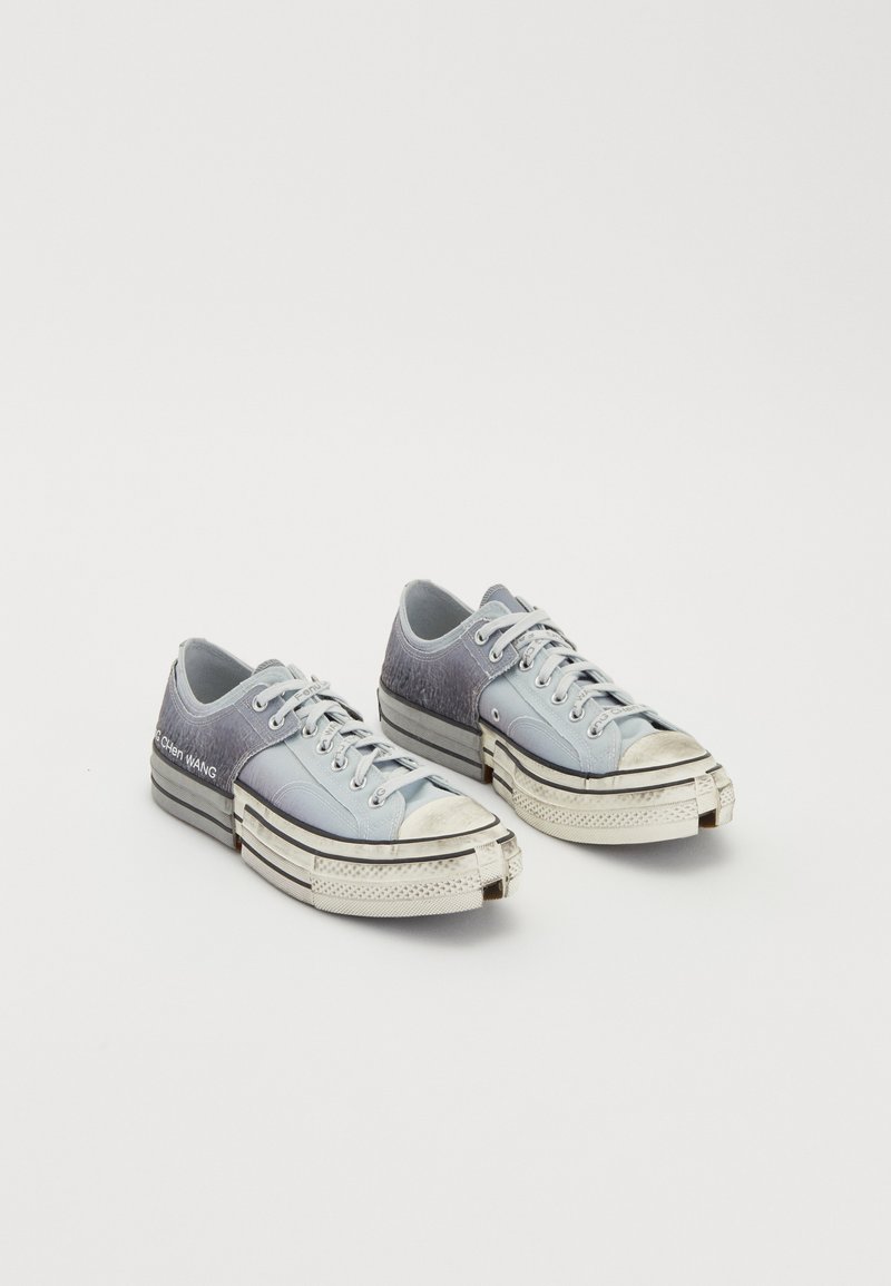 Helltürkisfarbene Canvas-Sneaker mit Ombre-Design, strukturiertem Rückenteil, weißen Sohlen und schwarzen Akzentlinien. Abgenutzte Zehenkappen und Logo-Detail.