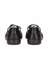 Une paire de baskets en cuir noir et marron foncé avec des zippers sur les côtés, vue de l'arrière sur un fond blanc.