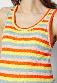 Topp i ärmlös stil tillverkad av texturerad tyg med horisontella ränder i orange, gult, ljusblått och rosa, med rund halsringning och ribbade kanter.