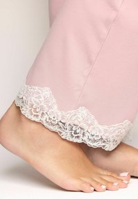 Vaaleanpunaiset pyjamasousut, joissa on ribbikuvio ja valkoinen pitsihelma, esittelevät kukkakuosia ja pehmeää, kevyttä kangasta.