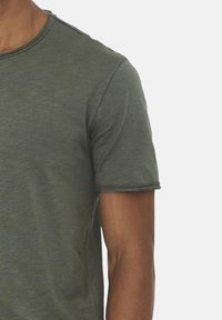 Oliven grøn kortærmet T-shirt i et blødt, let stof med rund halsudskæring og diskrete stikninger langs kanterne.