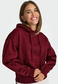 Felpa marsala realizzata in materiale morbido, con tasca frontale, cappuccio con coulisse e polsini a costine. Design semplice e rilassato.