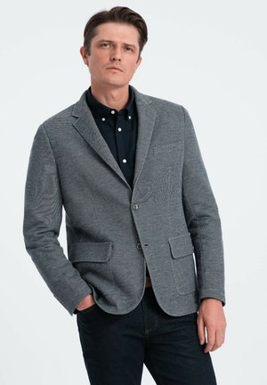 Grau gestreifter Blazer mit tailliertem Schnitt, Reverskragen und zwei vorderen Taschen, getragen über einem schwarzen Button-up-Hemd.