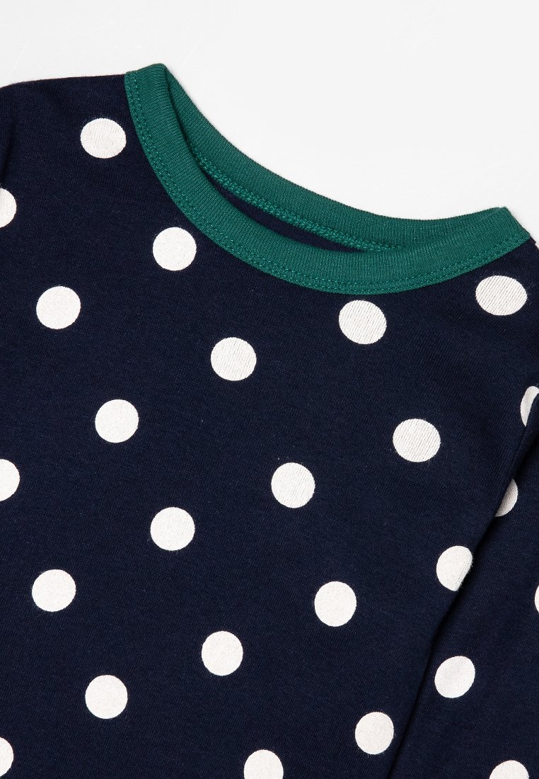 Chemise à manches longues bleu marine ornée de pois blancs, avec un col ras du cou côtelé vert contrastant et en matériau coton doux.