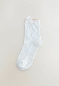 Balts zeķes, kas izgatavotas no mīksta materiāla, ar dekoratīvu dimanta rakstu un lielu, piesietu lentu augšpusē. Visā virsmā ir gluda tekstūra.