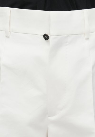 Witte broek gemaakt van gladde stof, met een enkele zwarte knoop, een vlak front en minimale stikseldetails. Getailleerd model.