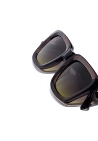 Occhiali da sole con spesse montature in plastica marrone scuro e lenti sfumate, caratterizzati da una forma quadrata e bordi arrotondati.
