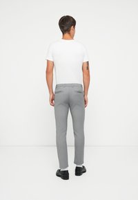 Pantalones grises ajustados con un corte slim, que cuentan con bolsillos laterales, una textura suave y una cintura con passtas para cinturón, combinados con una camiseta blanca.