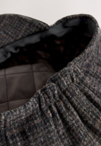 Siva i smeđa tkanina torba s rebrastom teksturom i elastičnim gornjim rubom, sadrži glatku crnu navlaku i suptilan karo uzorak iznutra.