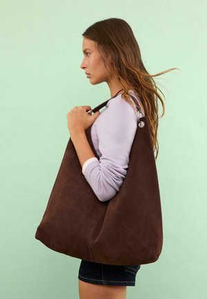 Braune Wildleder-Schultertasche mit einem lässigen Design, das eine glatte Textur und eine metallische Akzentuierung am Riemen aufweist.
