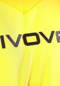 Maglia sportiva gialla realizzata in tessuto in rete traspirante. Presenta grandi lettere nere che formano la parola "VOVR" sulla parte anteriore.