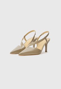 Slingback pointed-toe heels in taupe satin, featuring a slender heel and crisscross strap design. Smooth texture with minimal hardware accents.