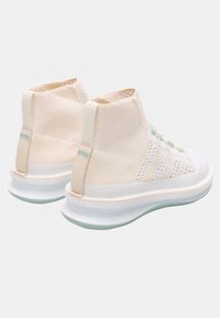 Lyse beige high-top sneakers lavet af åndbart materiale, med et struktureret ribbet design, snørebånd foran og en blød hvid sål med mintfarvede accenter.