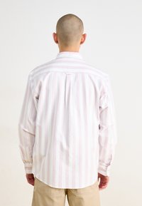 Camisa de botones con rayas verticales rosas y blancas, de mangas largas y con cuello. El material parece ligero y similar al algodón.