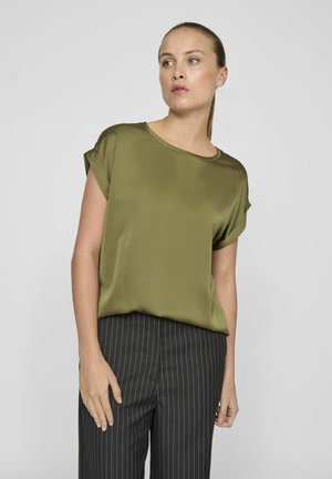 Olijfgroene blouse met korte mouwen van een gladde stof, voorzien van een ronde halslijn en opgerolde mouwen, gecombineerd met zwarte streepjesbroeken.