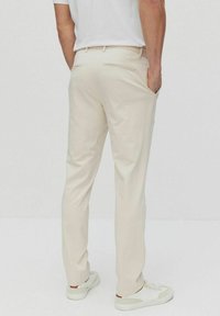 Ljust beige byxor med skräddarsydd passform, med bakfickor och en jämn textur, kombinerat med vita sneakers.