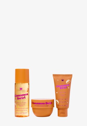 Il set per la cura del corpo Cinnamon Swirl include una bottiglia di spray trasparente, un barattolo rotondo di burro per il corpo e un tubo di gel doccia, il tutto in un packaging arancione con testo rosa.