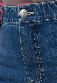 Mörkblå denimkjol med en metallisk knapp och sömnadsdetaljer. Har en slät textur och en figursydd midjeband.