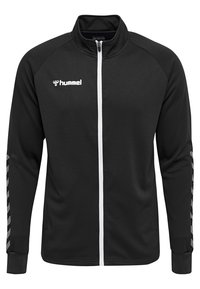 Chaqueta de chándal negra con un acabado texturizado, cremallera blanca en el frente y un logo en el pecho. Presenta rayas diagonales grises en las mangas.