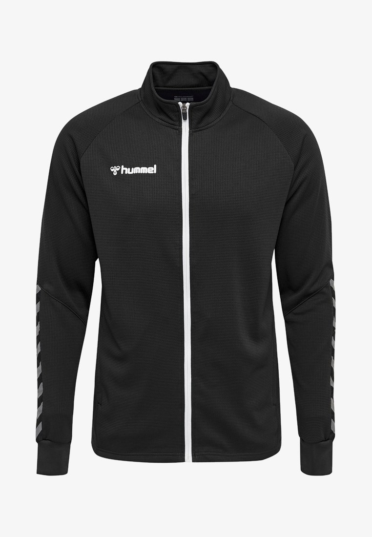 Chaqueta de chándal negra con un acabado texturizado, cremallera blanca en el frente y un logo en el pecho. Presenta rayas diagonales grises en las mangas.
